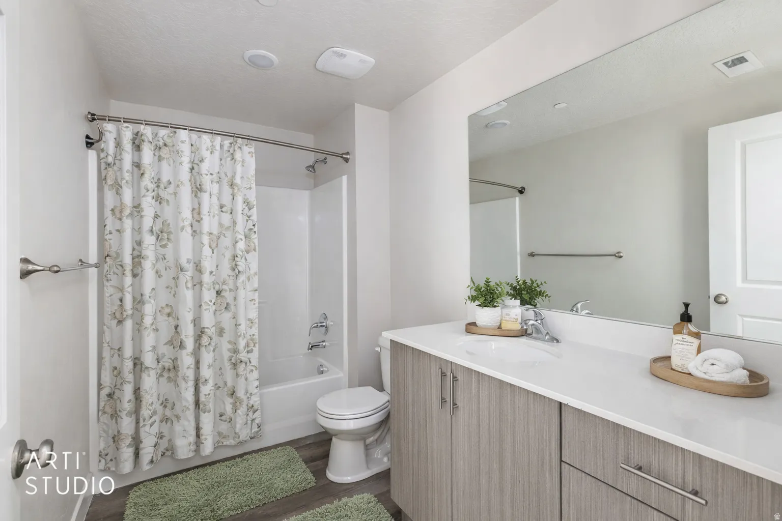 Bathroom with vanity, shower / tub combo with curtain, dark wood finished floors, and a textured ceiling