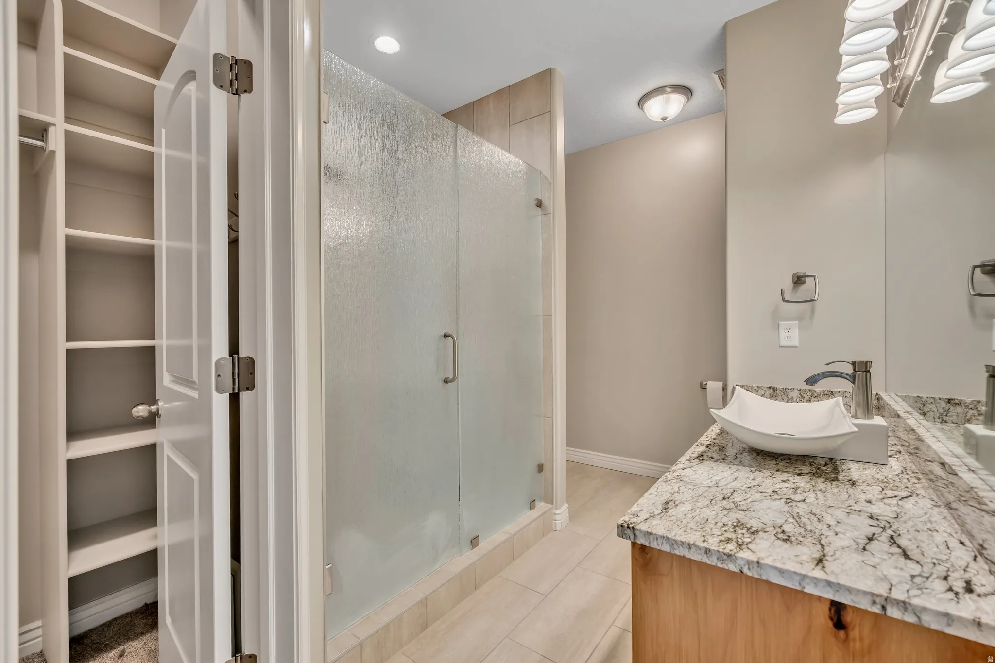 Full bath featuring vanity, a stall shower, light tile patterned floors, and recessed lighting