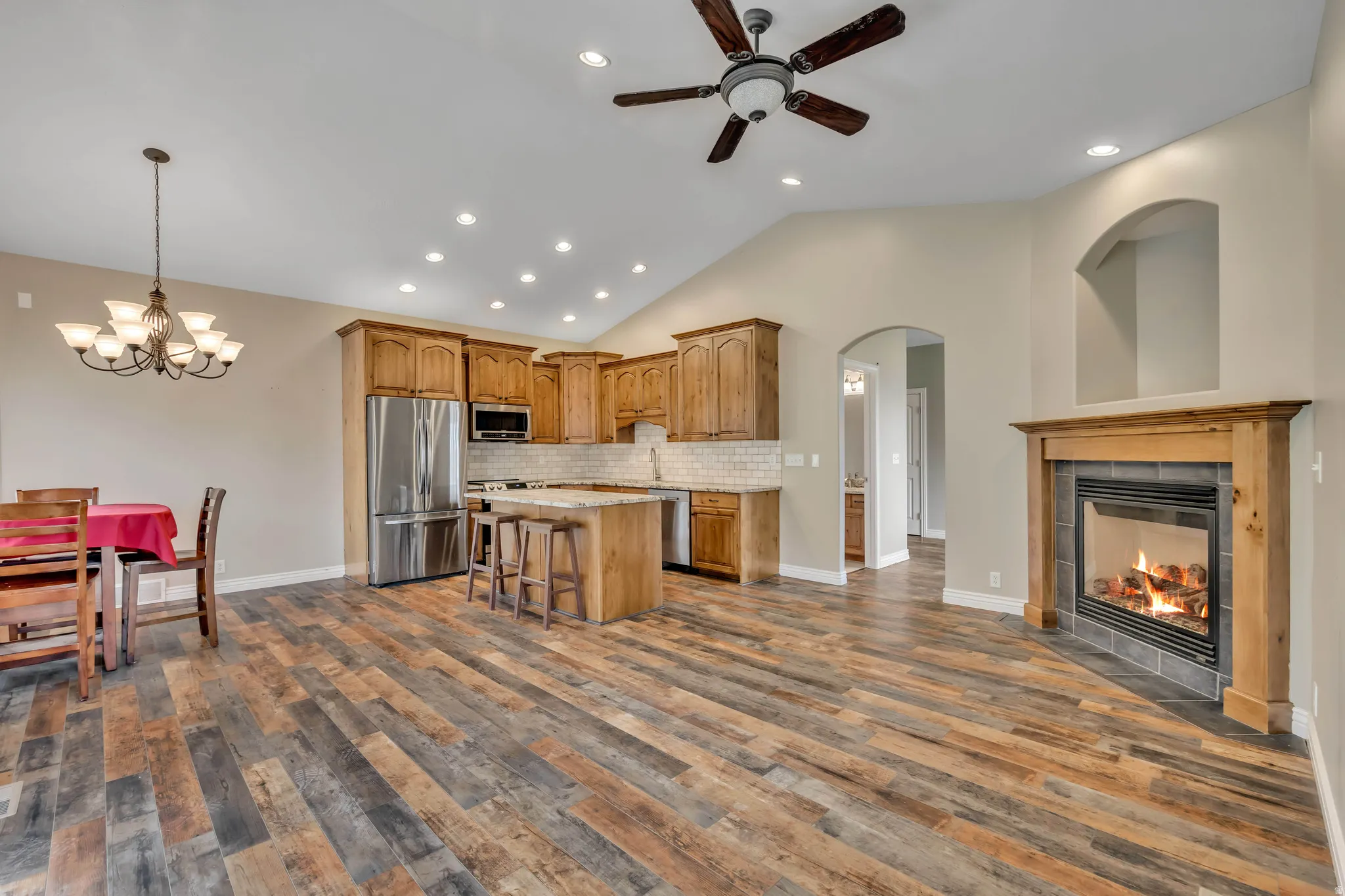 Kitchen with vaulted ceiling, a kitchen island, appliances with stainless steel finishes, a fireplace, and arched walkways