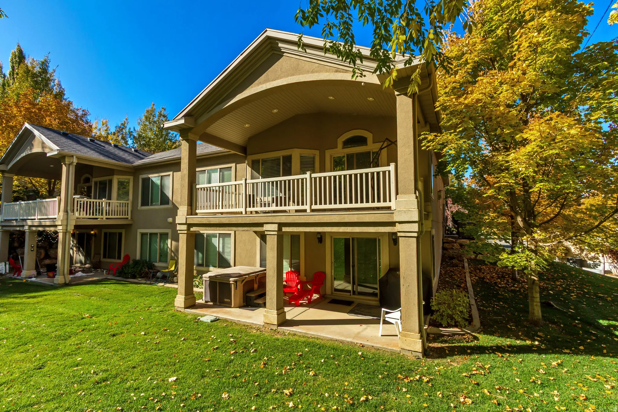 Rear view of house featuring a patio, stucco siding, a lawn, and a balcony