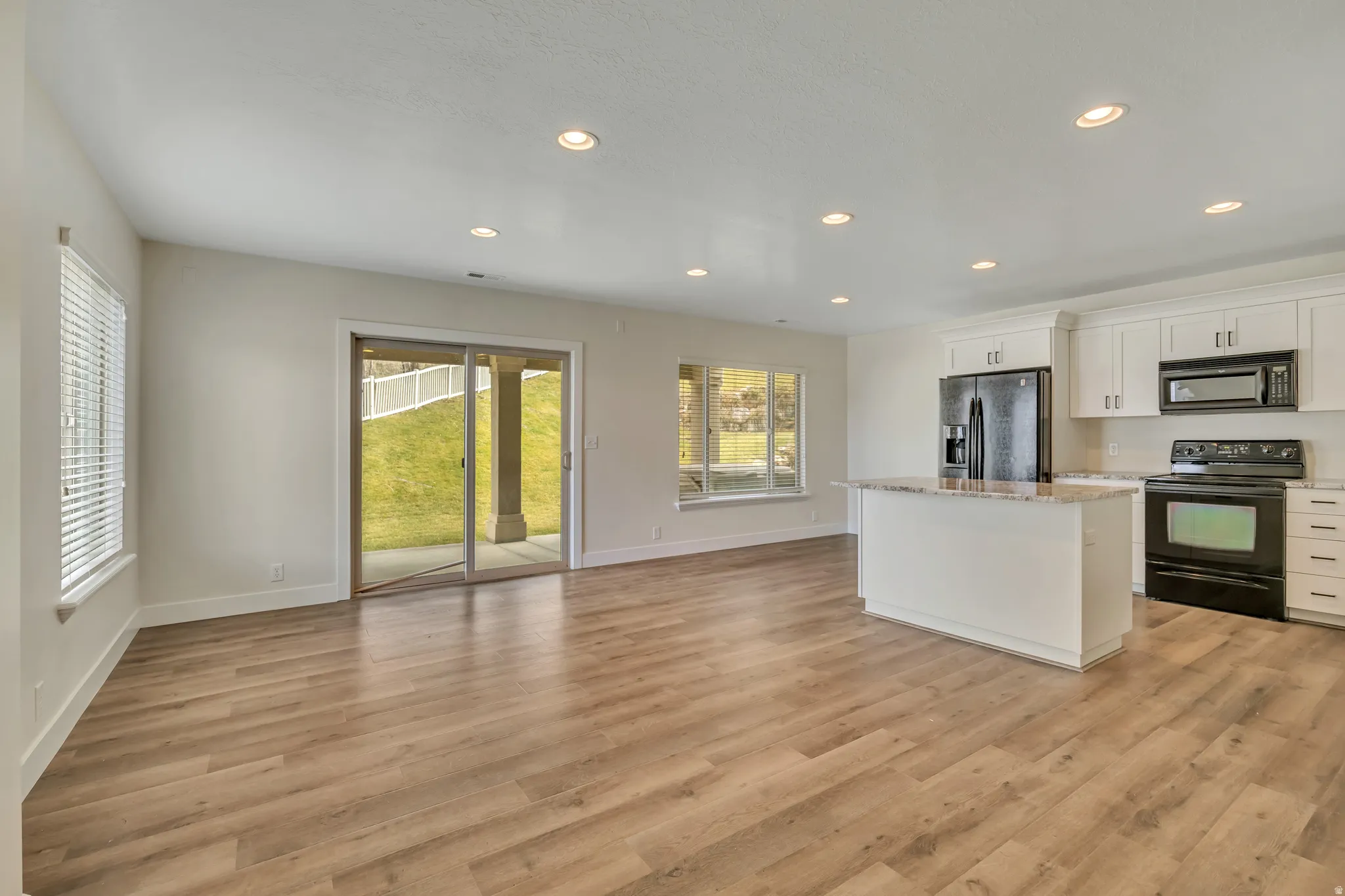 Kitchen with black appliances, a center island, white cabinetry, recessed lighting, and light wood-type flooring