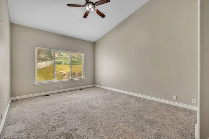 Spare room with vaulted ceiling, ceiling fan, and carpet