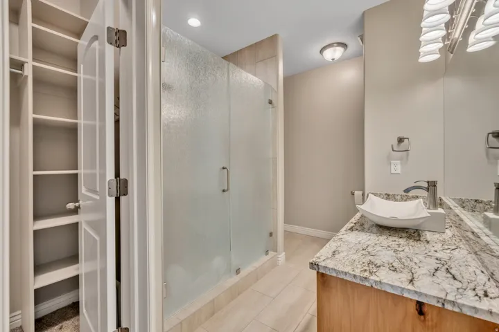Full bath featuring vanity, a stall shower, light tile patterned floors, and recessed lighting