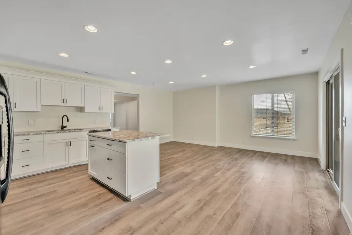 Kitchen featuring light stone countertops, white cabinets, recessed lighting, a center island, and open floor plan