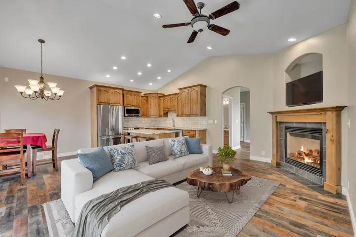 Living area with vaulted ceiling, dark wood finished floors, arched walkways, a tile fireplace, and recessed lighting