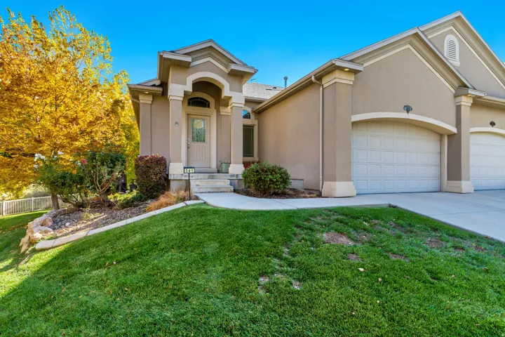 View of front of home with stucco siding, driveway, an attached garage, and a front yard