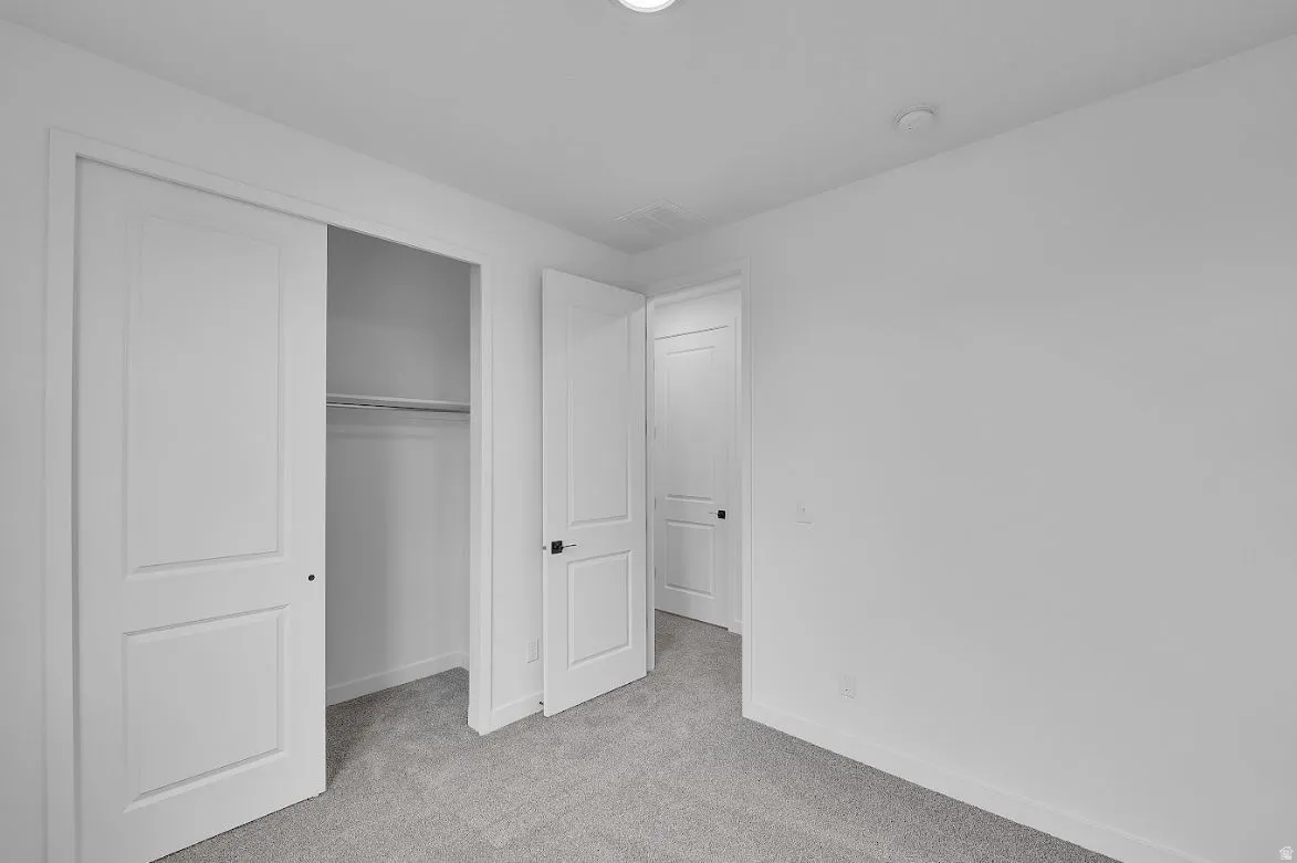 Unfurnished bedroom featuring light colored carpet and a closet