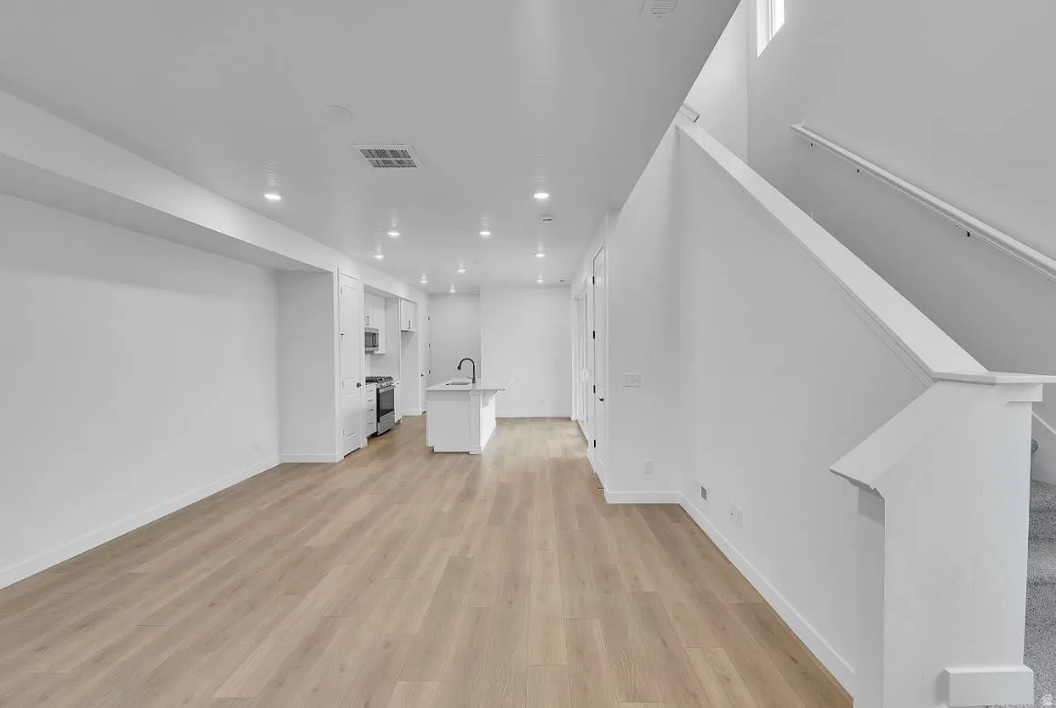 Unfurnished living room with light wood-style flooring, recessed lighting, and stairs