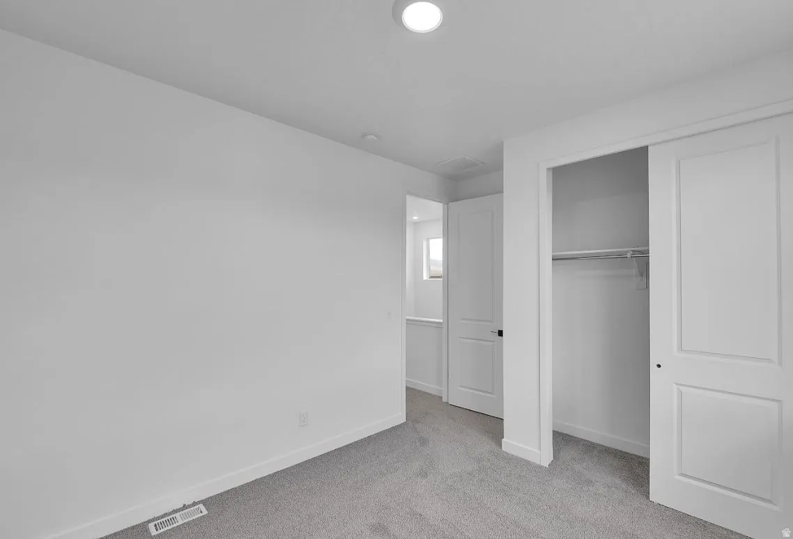 Unfurnished bedroom with light colored carpet and a closet