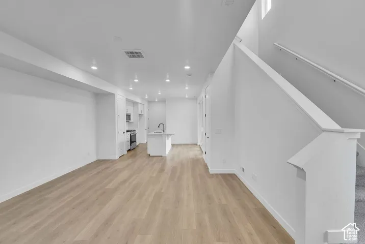 Unfurnished living room with light wood-style flooring, recessed lighting, and stairs
