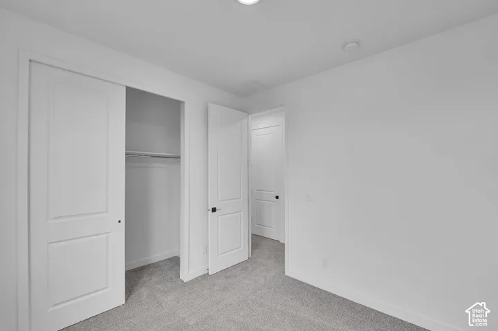 Unfurnished bedroom featuring light colored carpet and a closet
