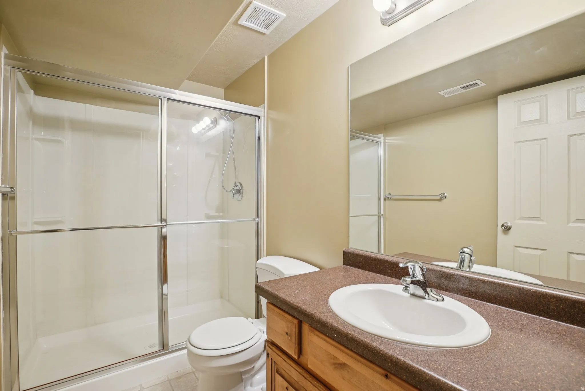 Full bath featuring vanity, a stall shower, and light tile patterned floors
