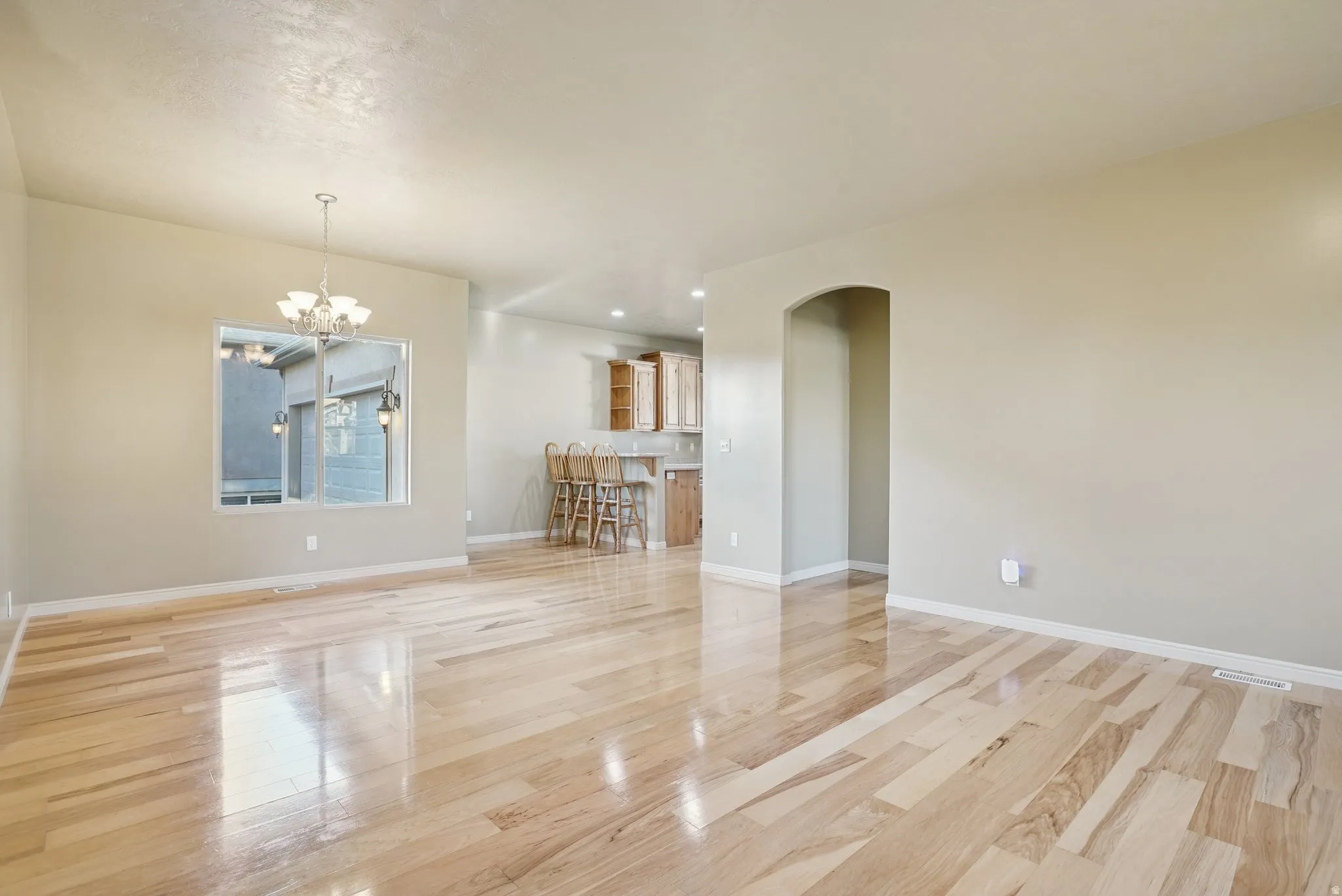 Unfurnished living room featuring arched walkways, a chandelier, recessed lighting, and light wood-style flooring