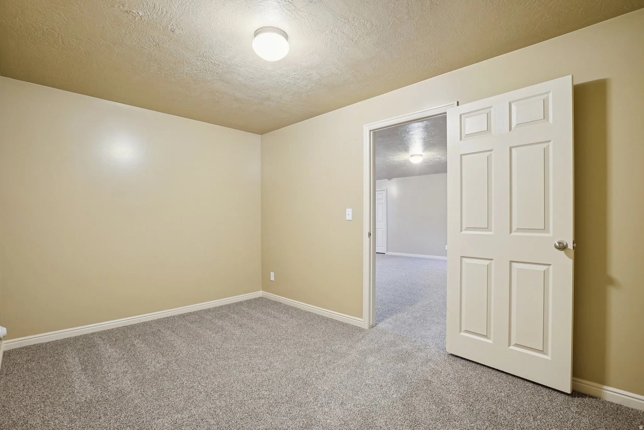 Unfurnished room with a textured ceiling and carpet flooring