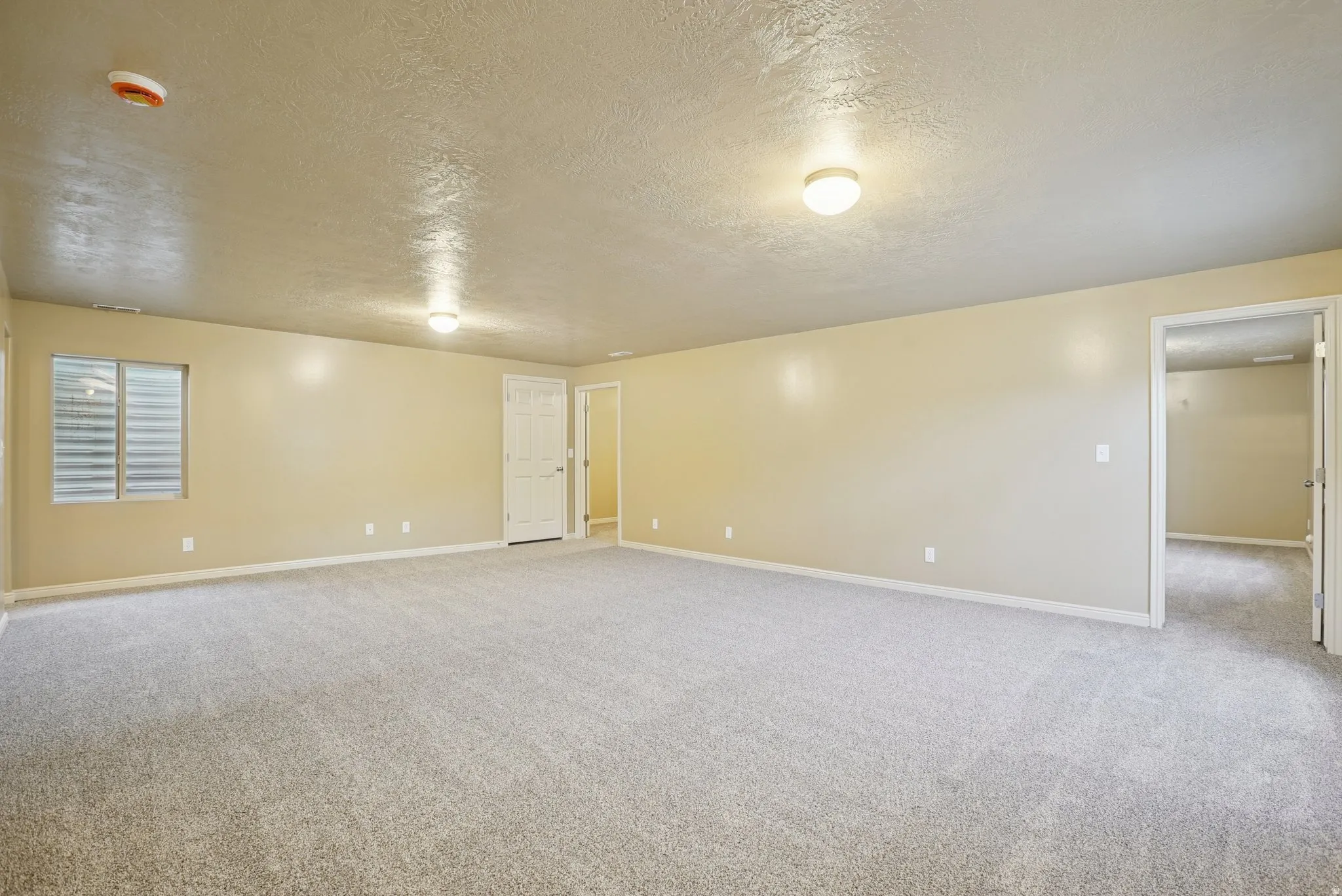 Spare room with a textured ceiling and light colored carpet