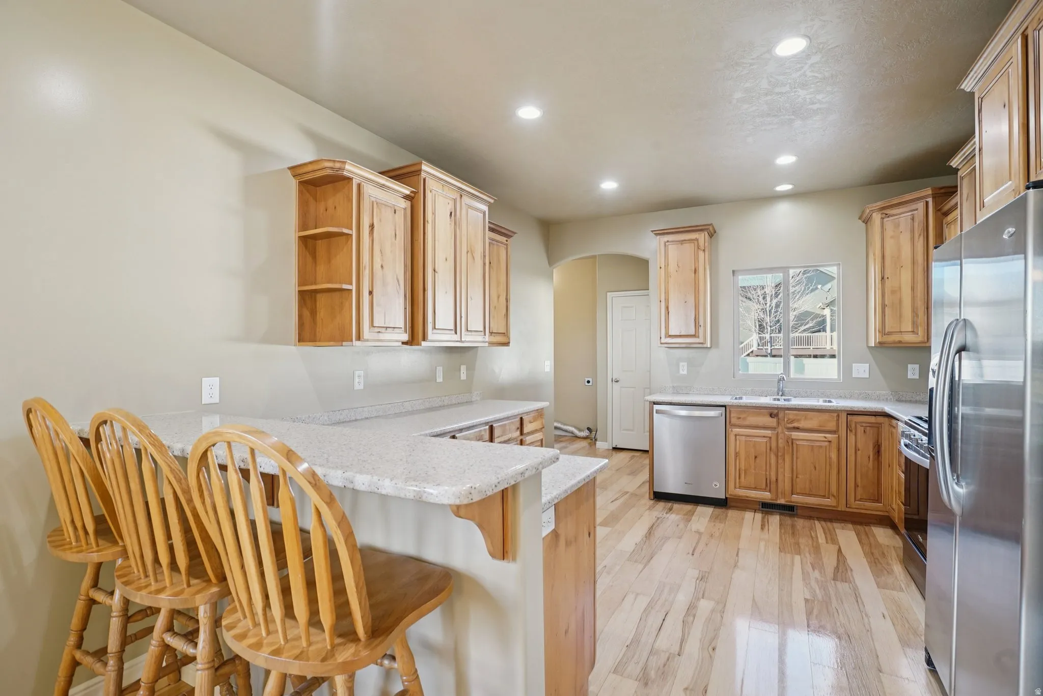 Kitchen featuring stainless steel appliances, recessed lighting, arched walkways, a peninsula, and open shelves