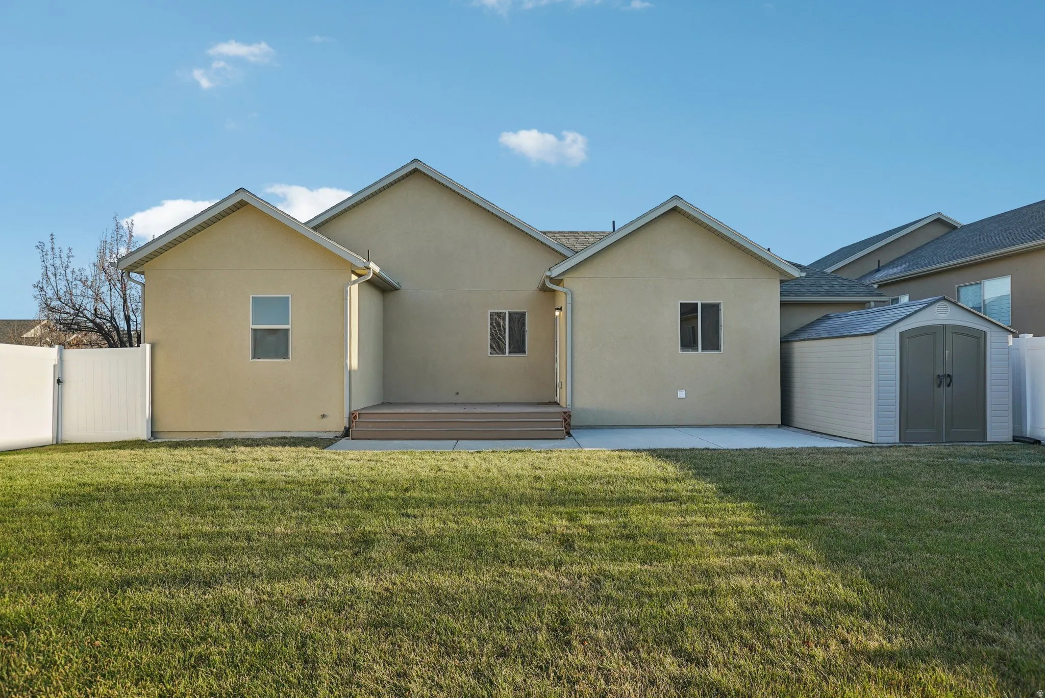 Back of property with a storage unit, stucco siding, a patio, and a gate