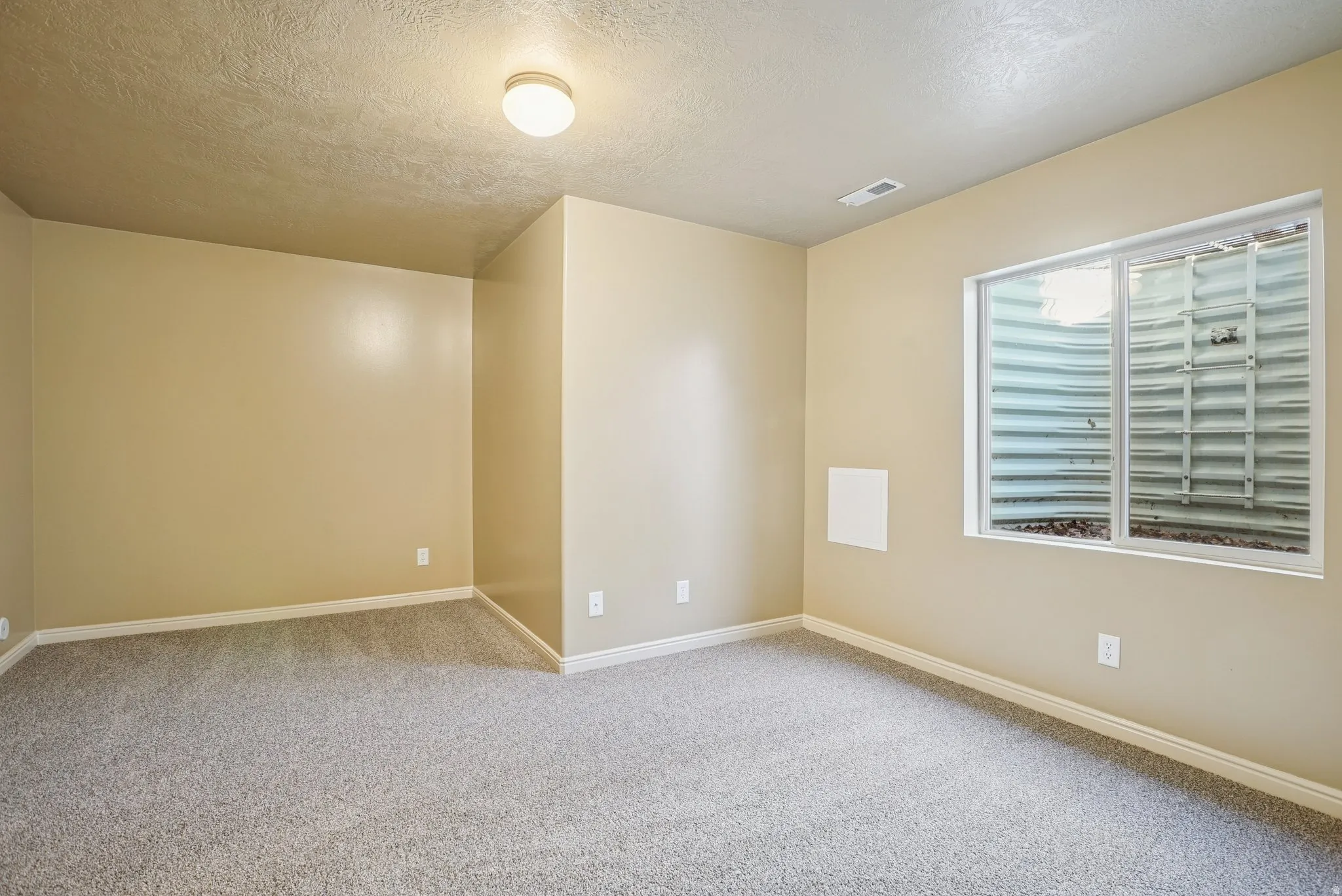 Carpeted spare room featuring a textured ceiling and baseboards