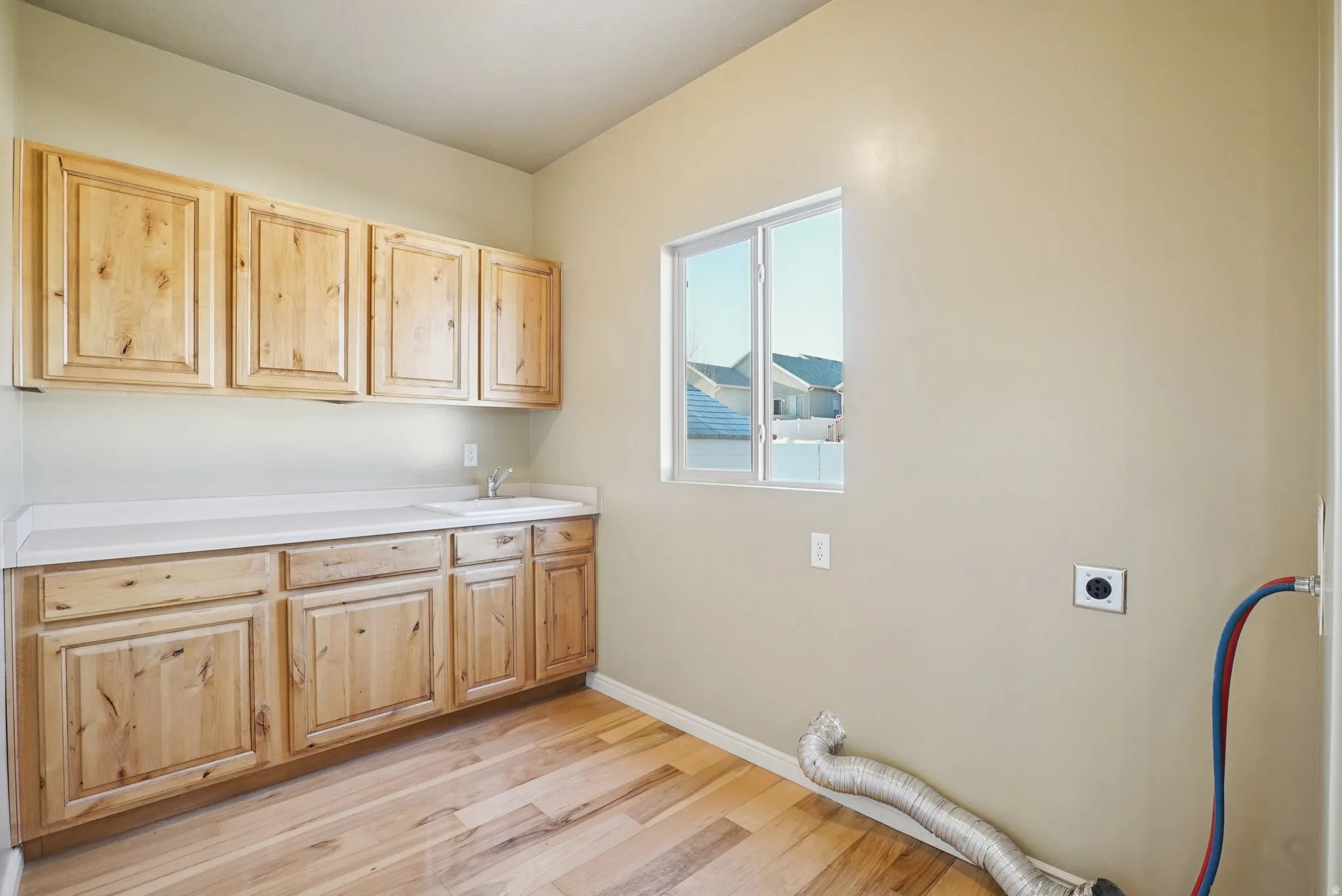 Laundry room featuring hookup for an electric dryer, light wood-type flooring, cabinet space, and hookup for a washing machine