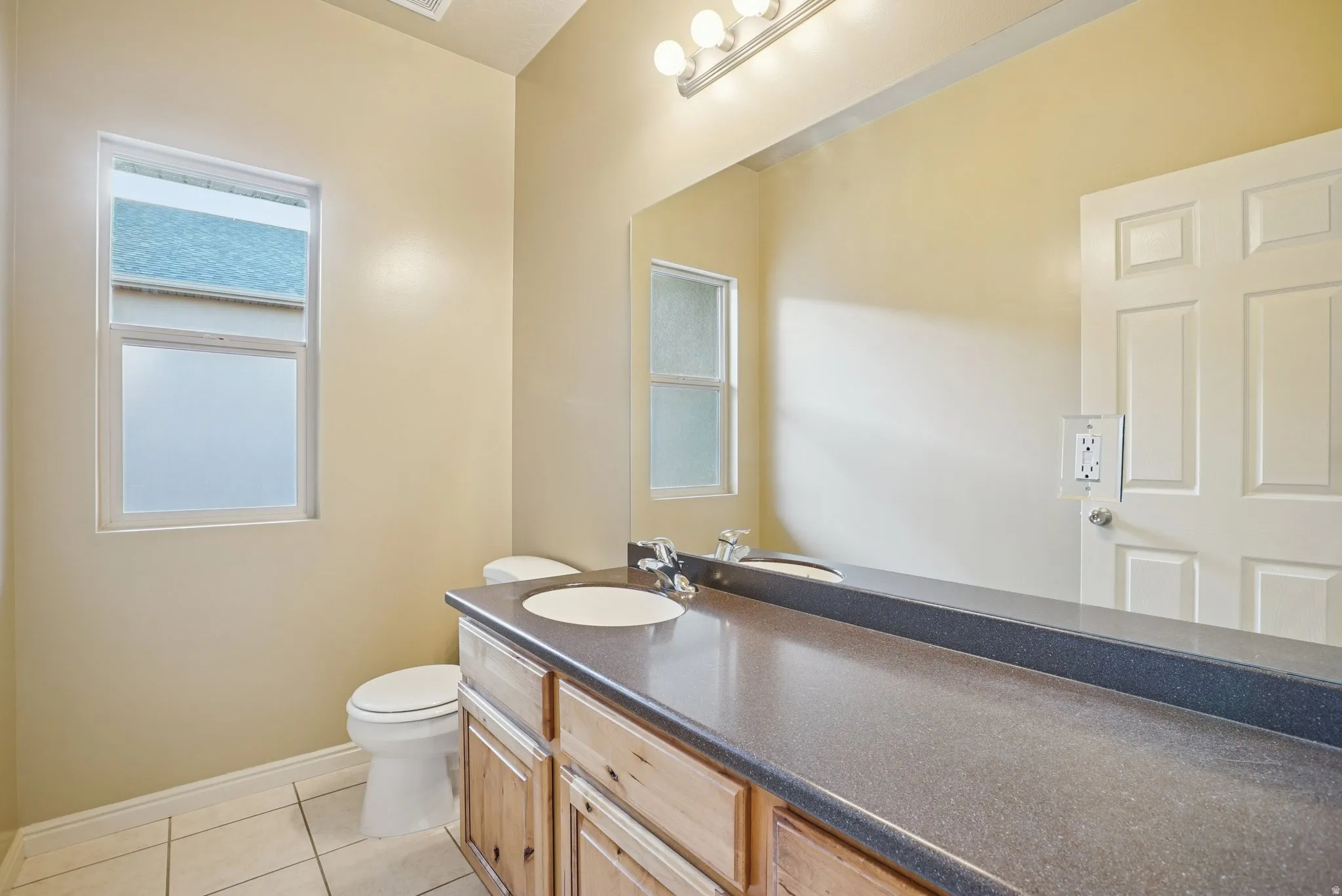 Half bathroom with vanity and light tile patterned flooring