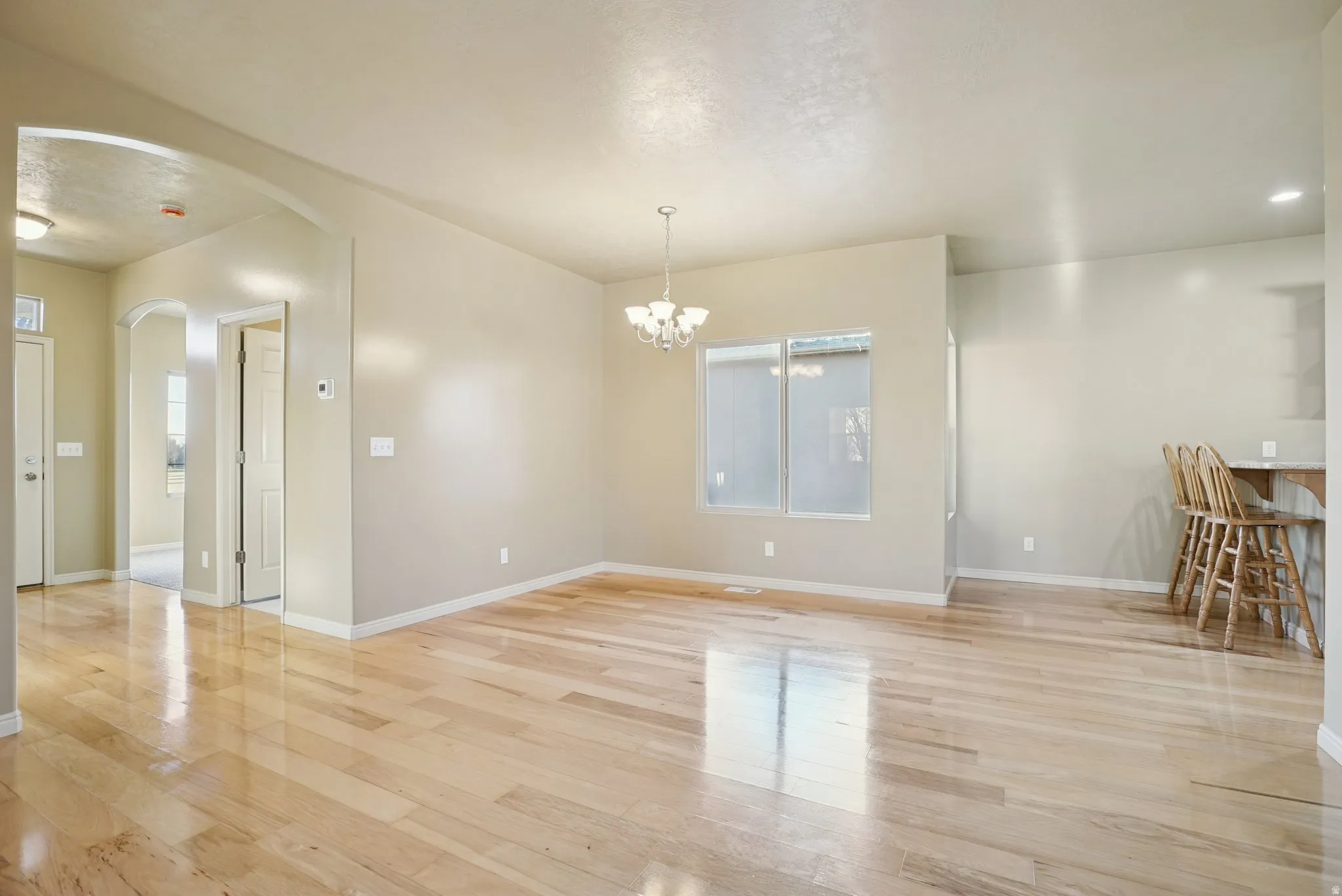 Unfurnished dining area featuring a chandelier, arched walkways, and light wood finished floors