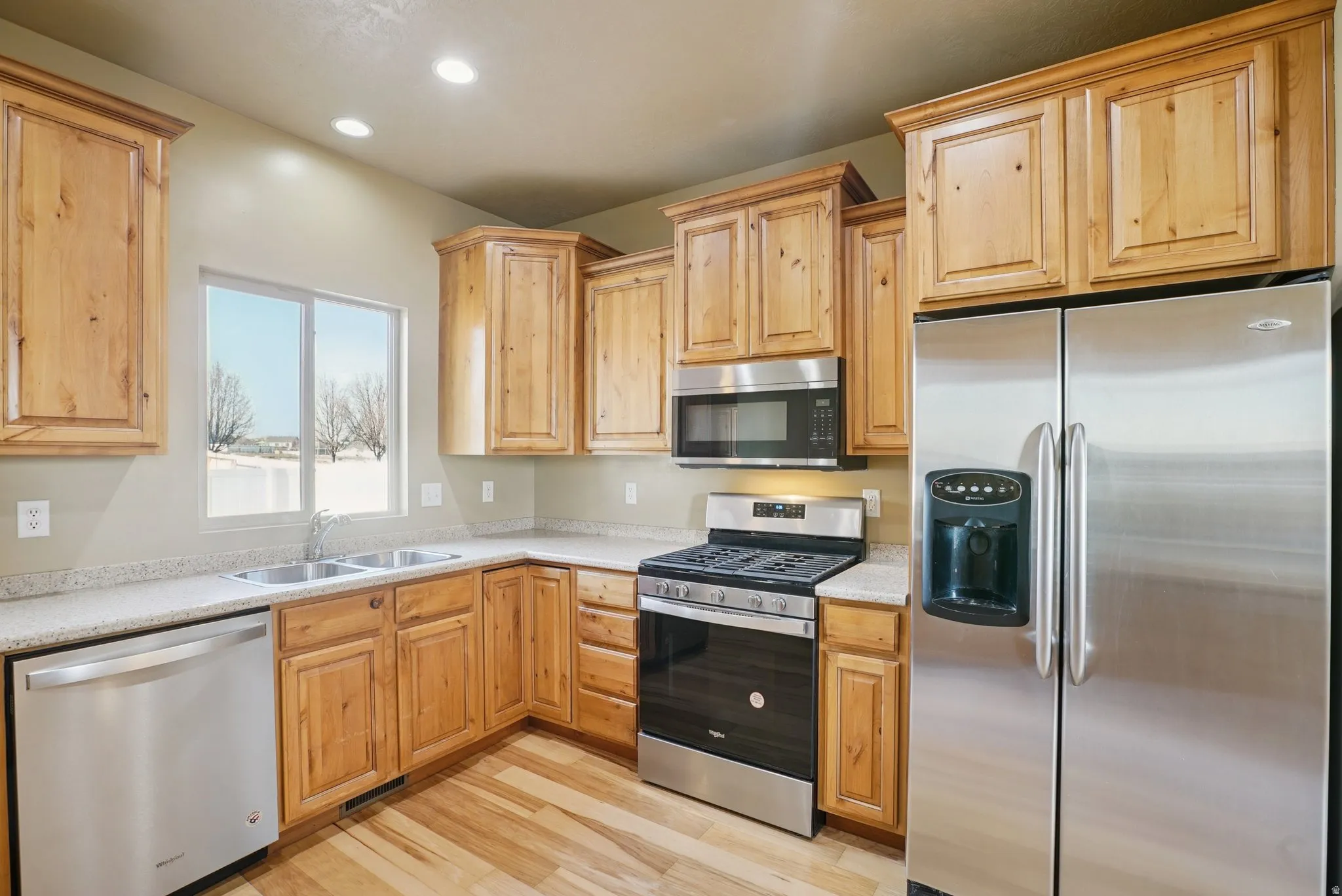 Kitchen with stainless steel appliances, light brown cabinetry, recessed lighting, and light wood-type flooring
