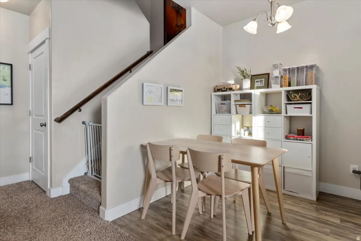 Dining room with a chandelier, wood finished floors, and stairs