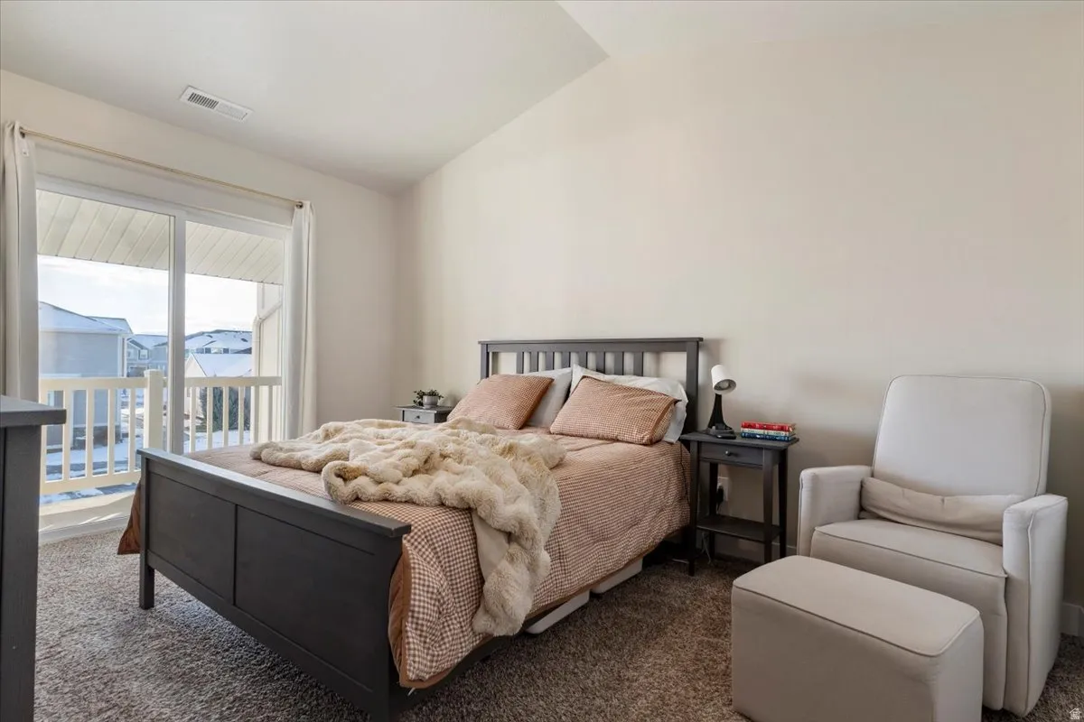 Carpeted primary bedroom featuring lofted ceiling and access to outside balcony