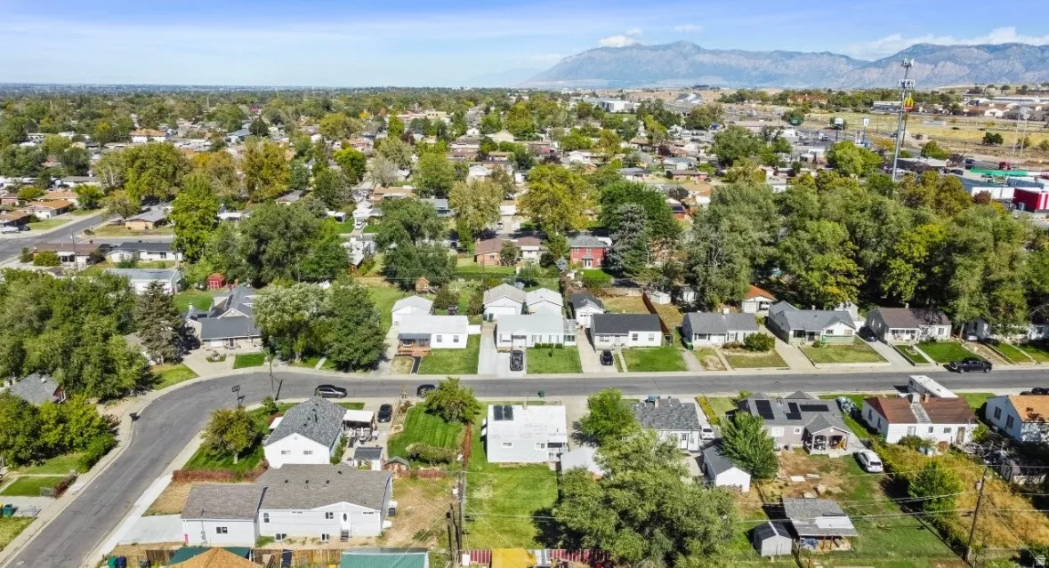 Aerial view of property and surrounding area featuring nearby suburban area and a mountain backdrop