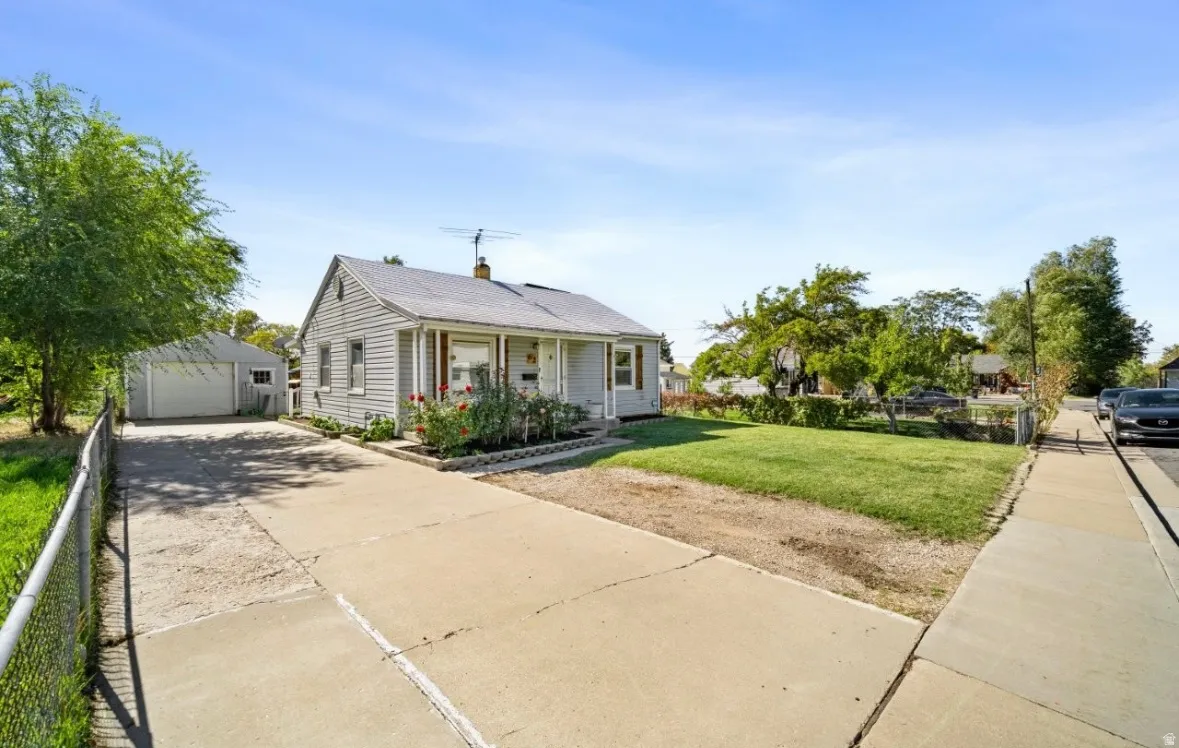 Bungalow with an outdoor structure, a front yard, covered porch, a detached garage, and concrete driveway