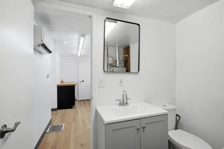 Half bathroom featuring vanity, an AC wall unit, and light wood-type flooring