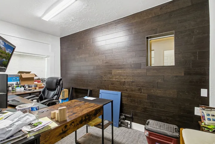 Office featuring wood walls and a textured ceiling