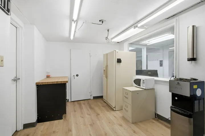 Kitchen featuring butcher block countertops, white appliances, light wood-type flooring, and dark cabinetry