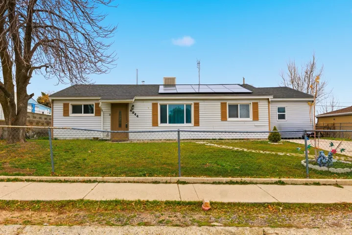 View of front of house with solar panels and a fenced front yard