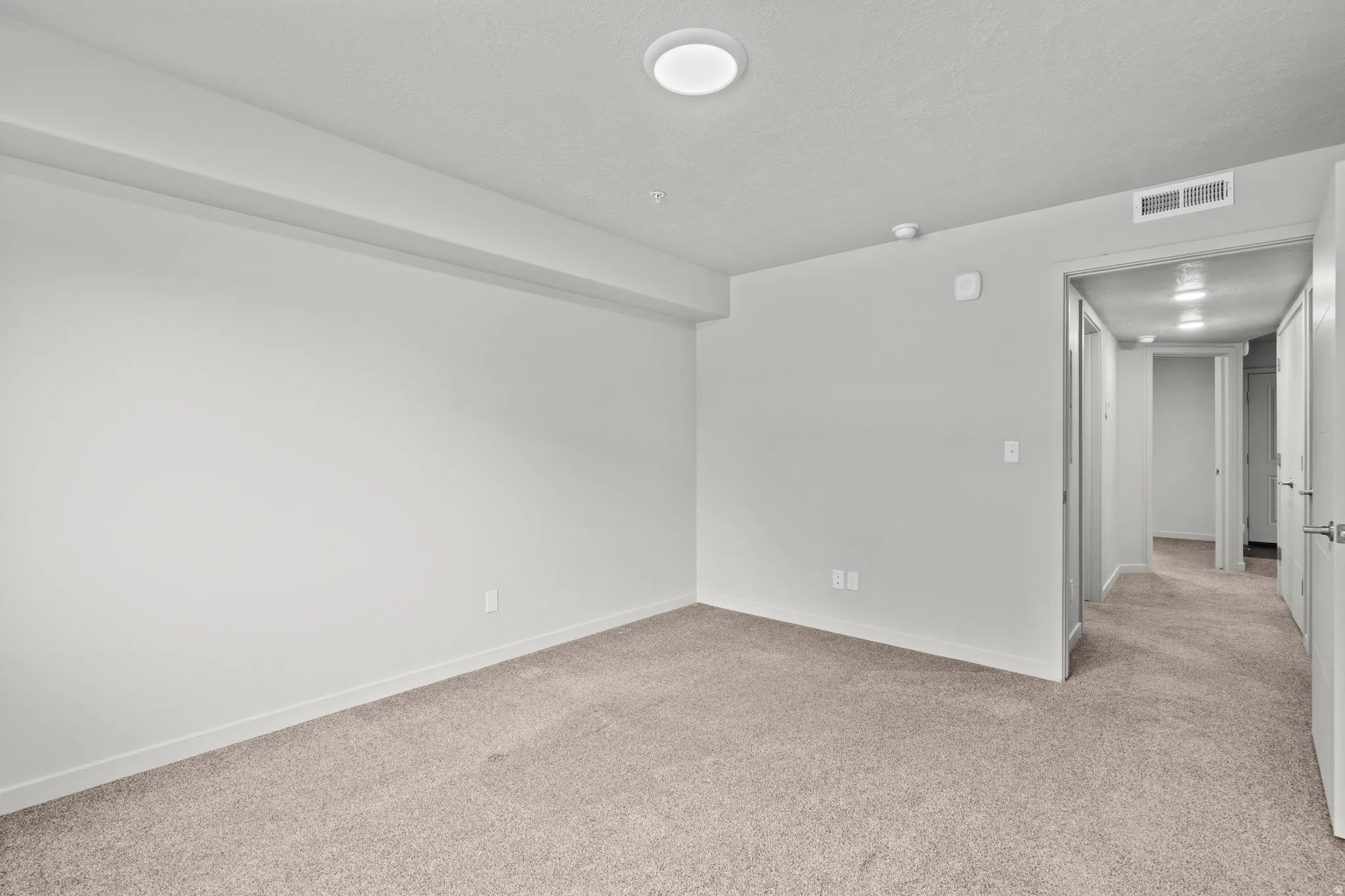Empty room with light carpet and a textured ceiling