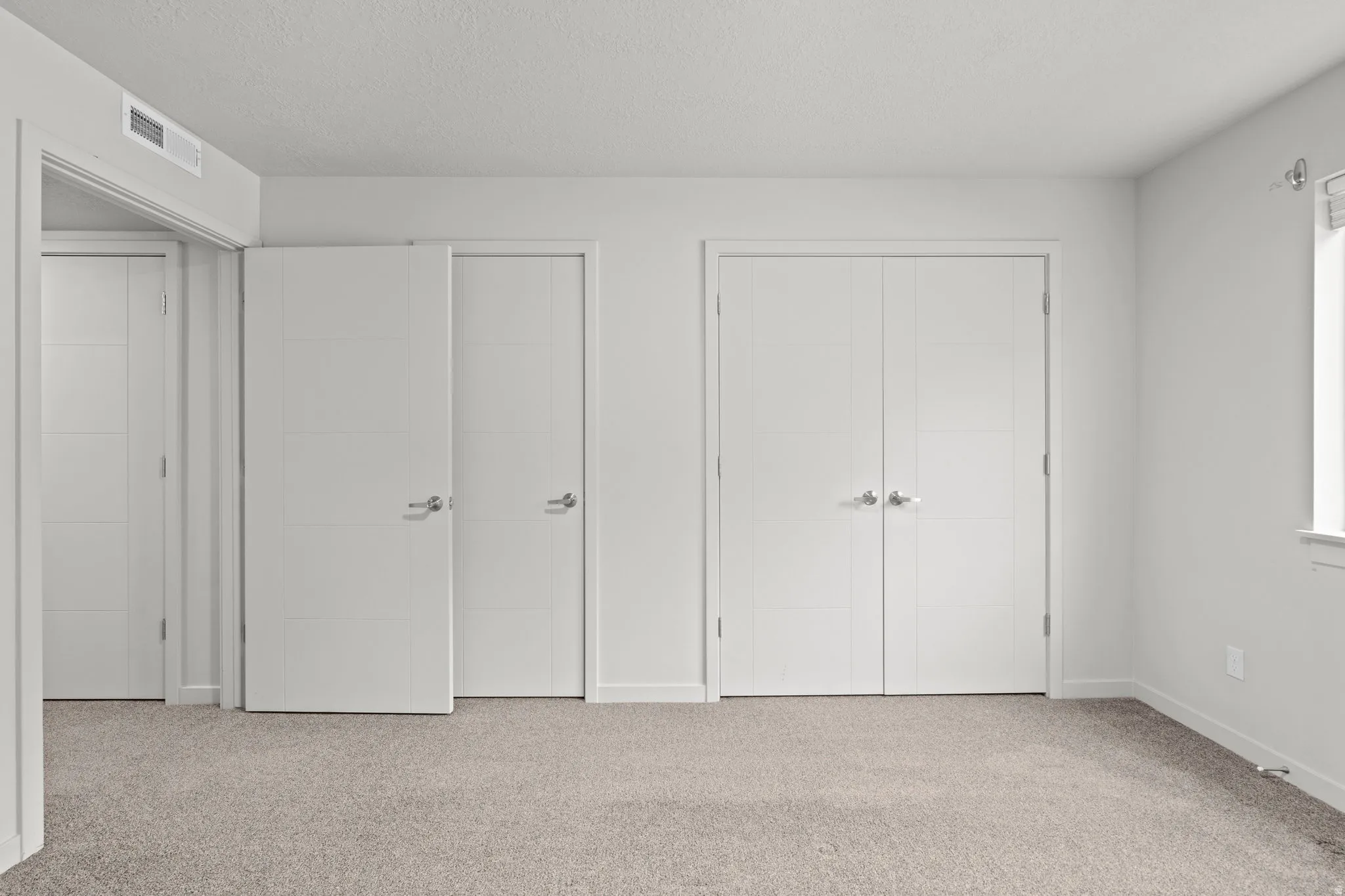Unfurnished bedroom featuring carpet floors, multiple closets, and a textured ceiling