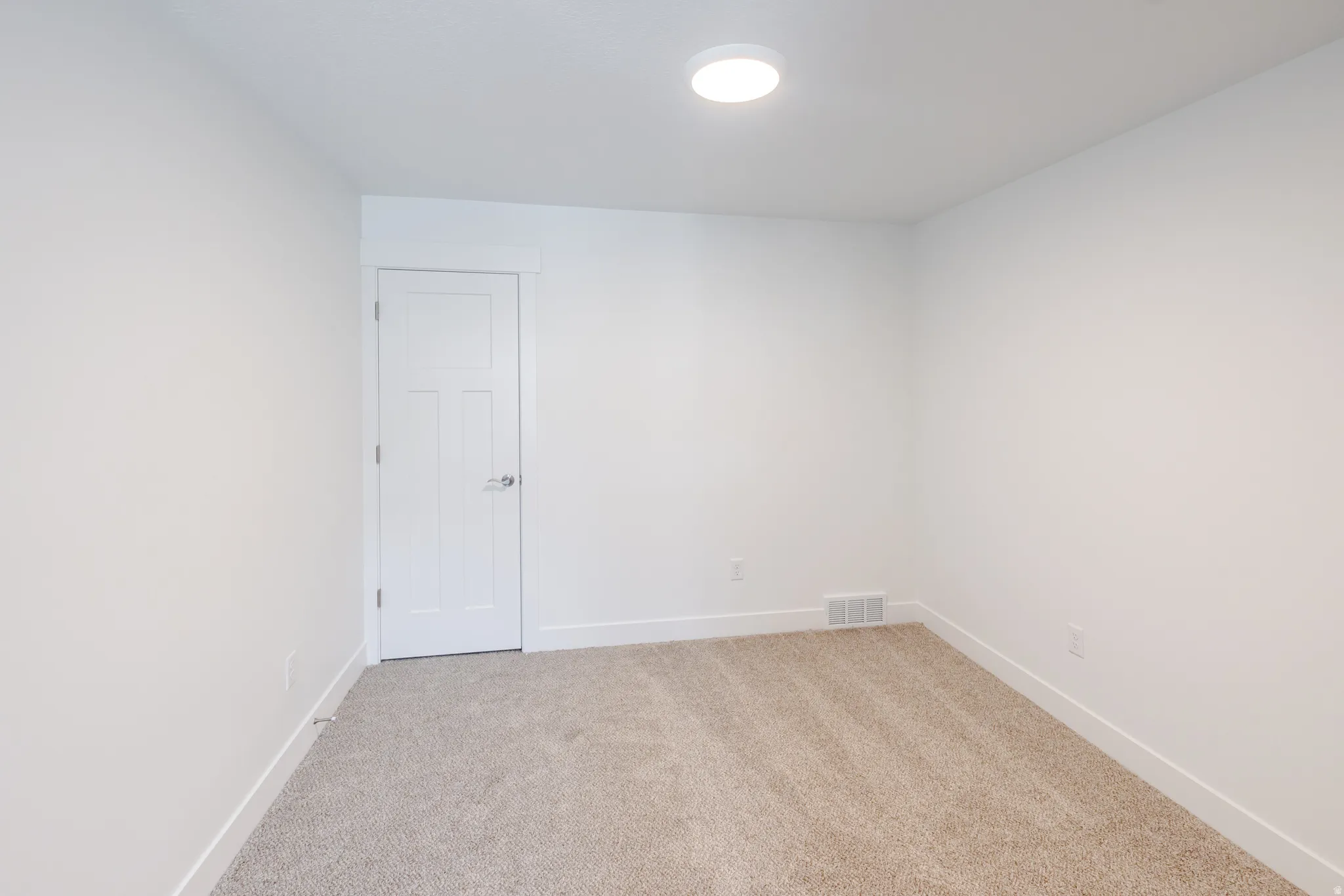 Neutral-toned carpeting paired with white baseboards and walls
