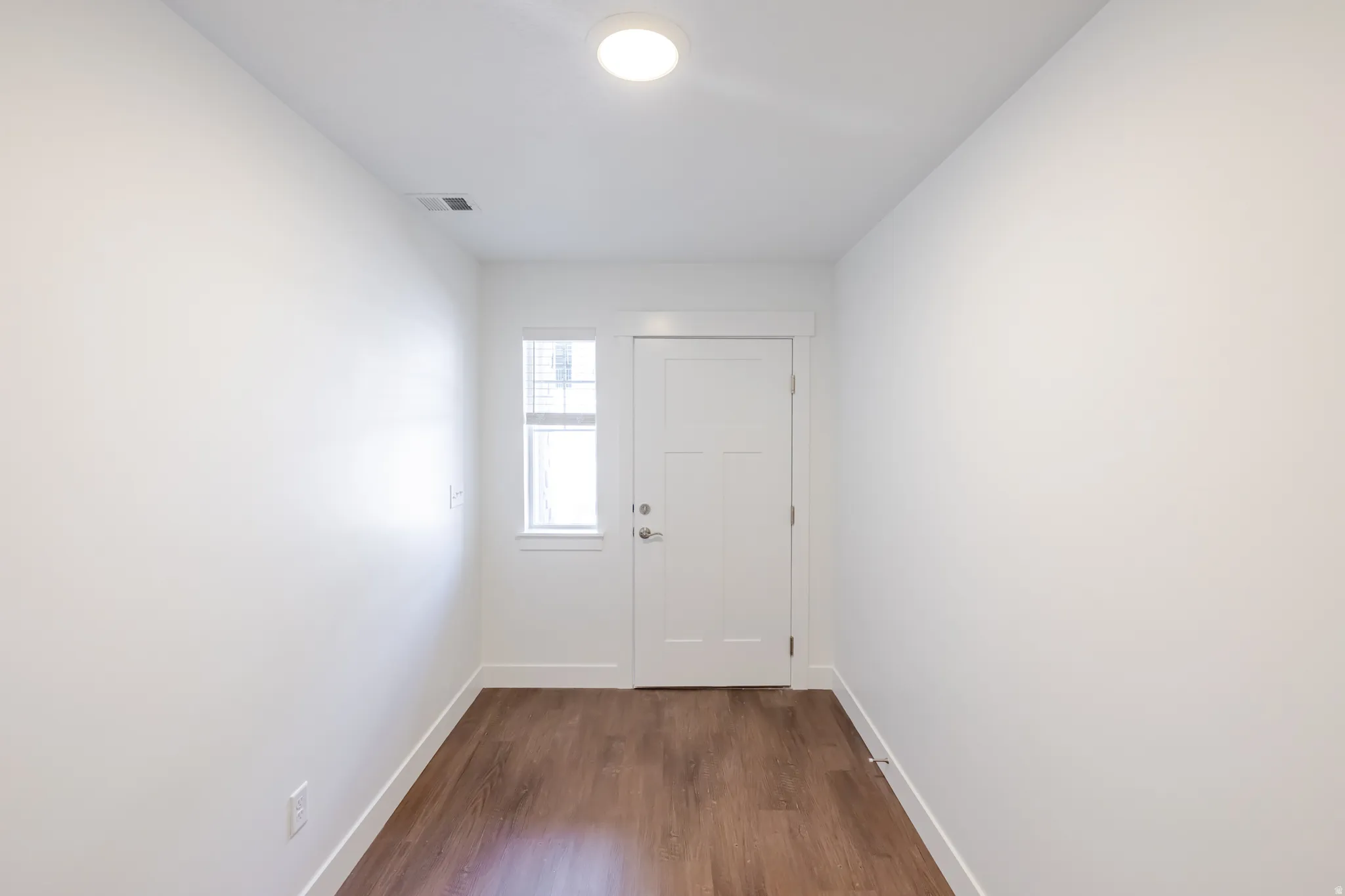 Entryway featuring wood-finish flooring, white walls, and a contemporary flush-mount ceiling light