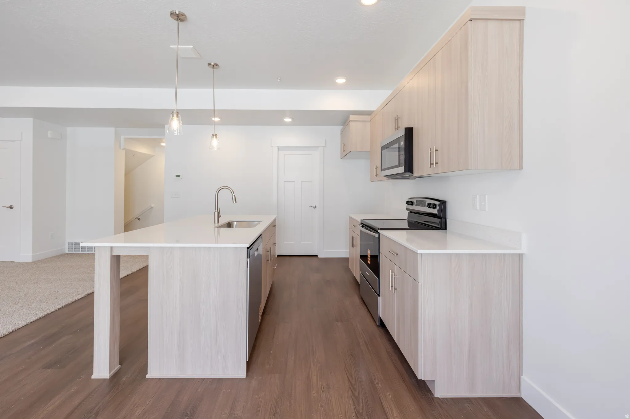 Contemporary kitchen featuring an expansive center island with a stainless steel sink and integrated dishwasher