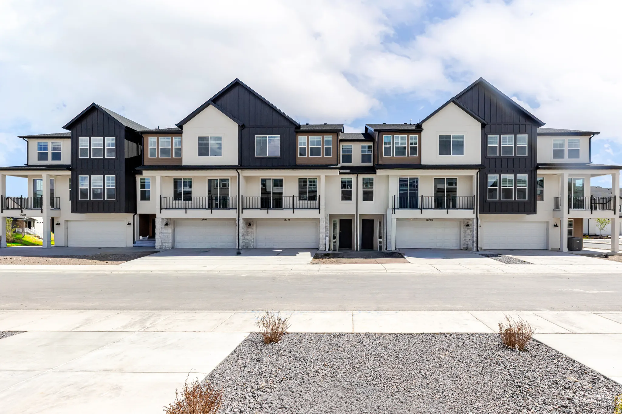 Modern townhome facades featuring dark vertical siding accents and light stucco