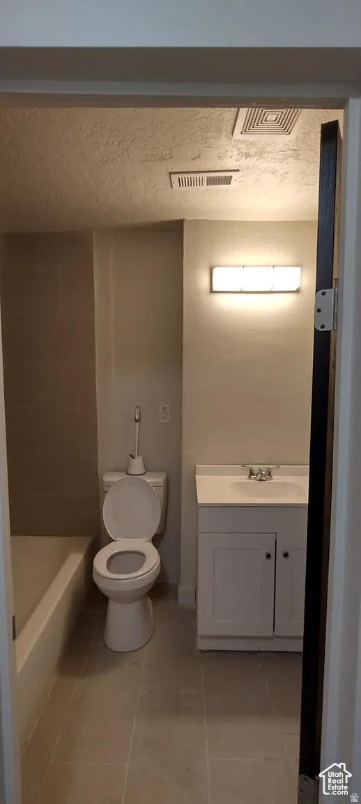 Full bathroom featuring vanity, light tile patterned flooring, and a textured ceiling