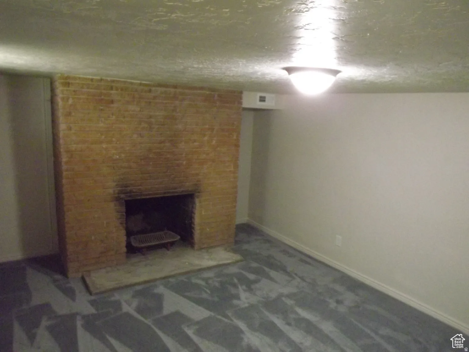 Finished basement with a brick fireplace, carpet flooring, and a textured ceiling