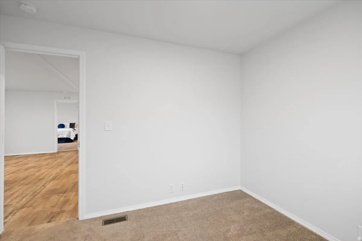 Carpeted empty room featuring baseboards and a smoke detector