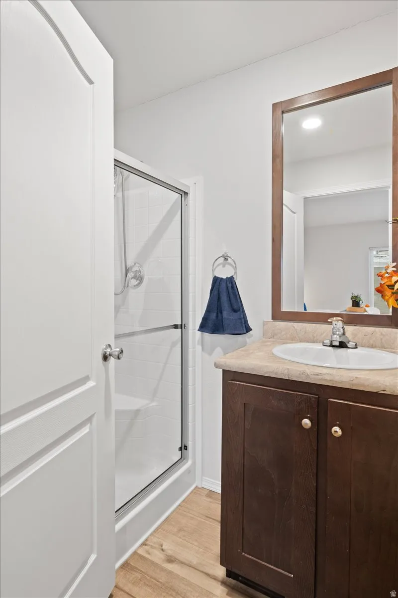 Bathroom featuring vanity, light wood finished floors, and a stall shower
