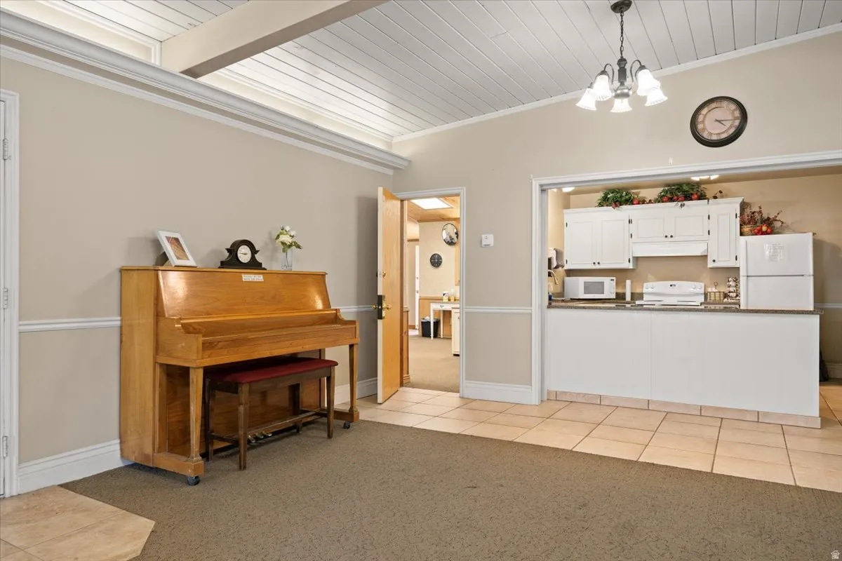 Living area with light colored carpet, wood ceiling, light tile patterned floors, a chandelier, and crown molding
