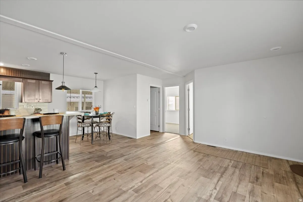 Kitchen featuring light countertops, a breakfast bar area, decorative light fixtures, light wood-style floors, and decorative backsplash