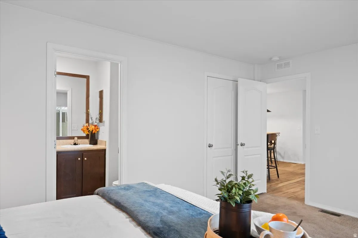 Carpeted bedroom featuring ensuite bath