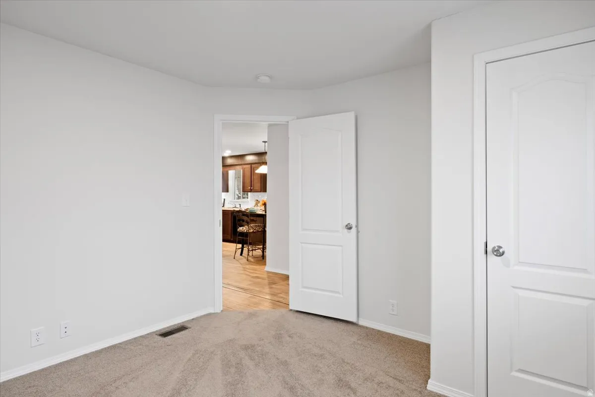 Unfurnished bedroom featuring light colored carpet and baseboards