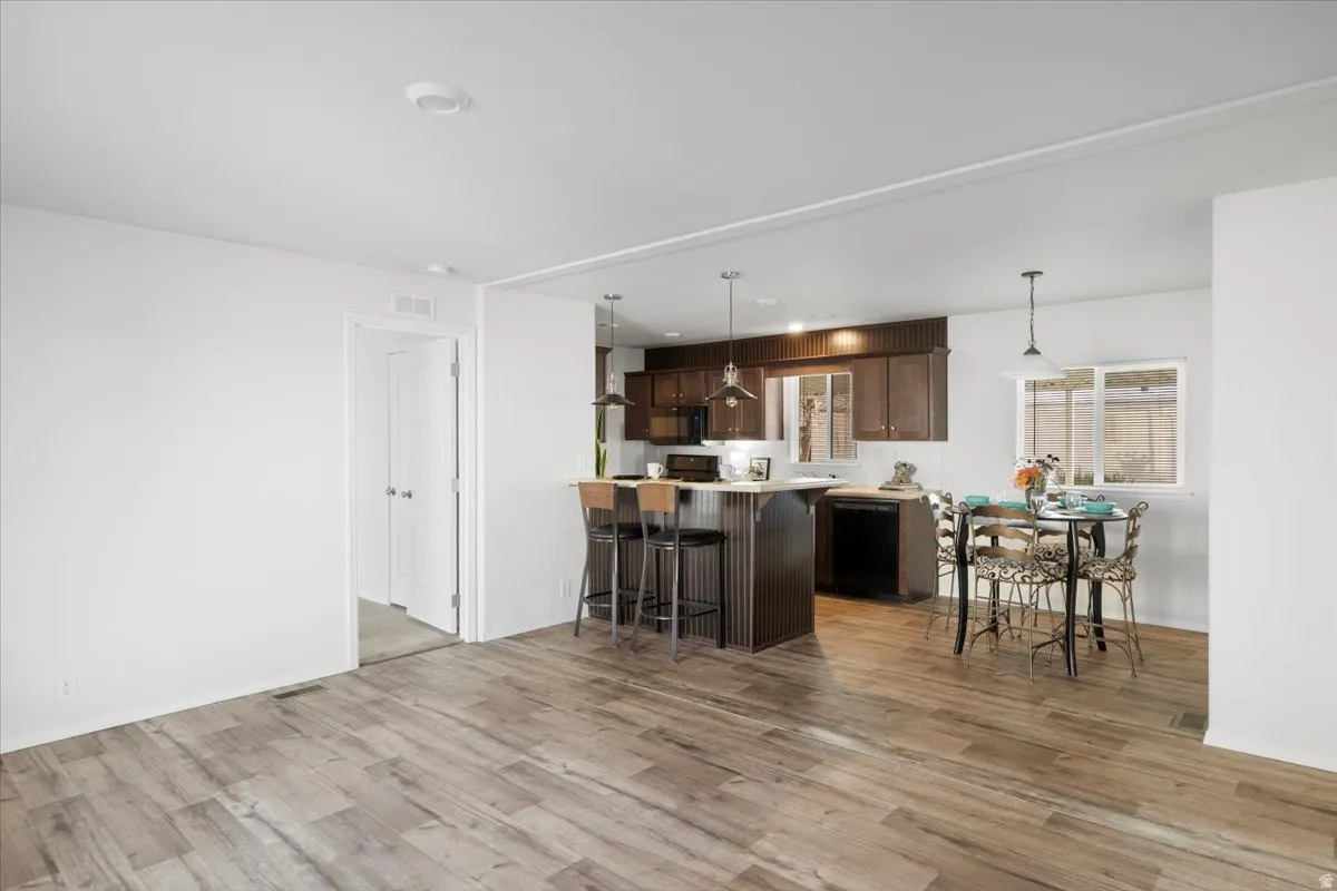 Kitchen with a peninsula, light countertops, a kitchen breakfast bar, dark brown cabinetry, and pendant lighting