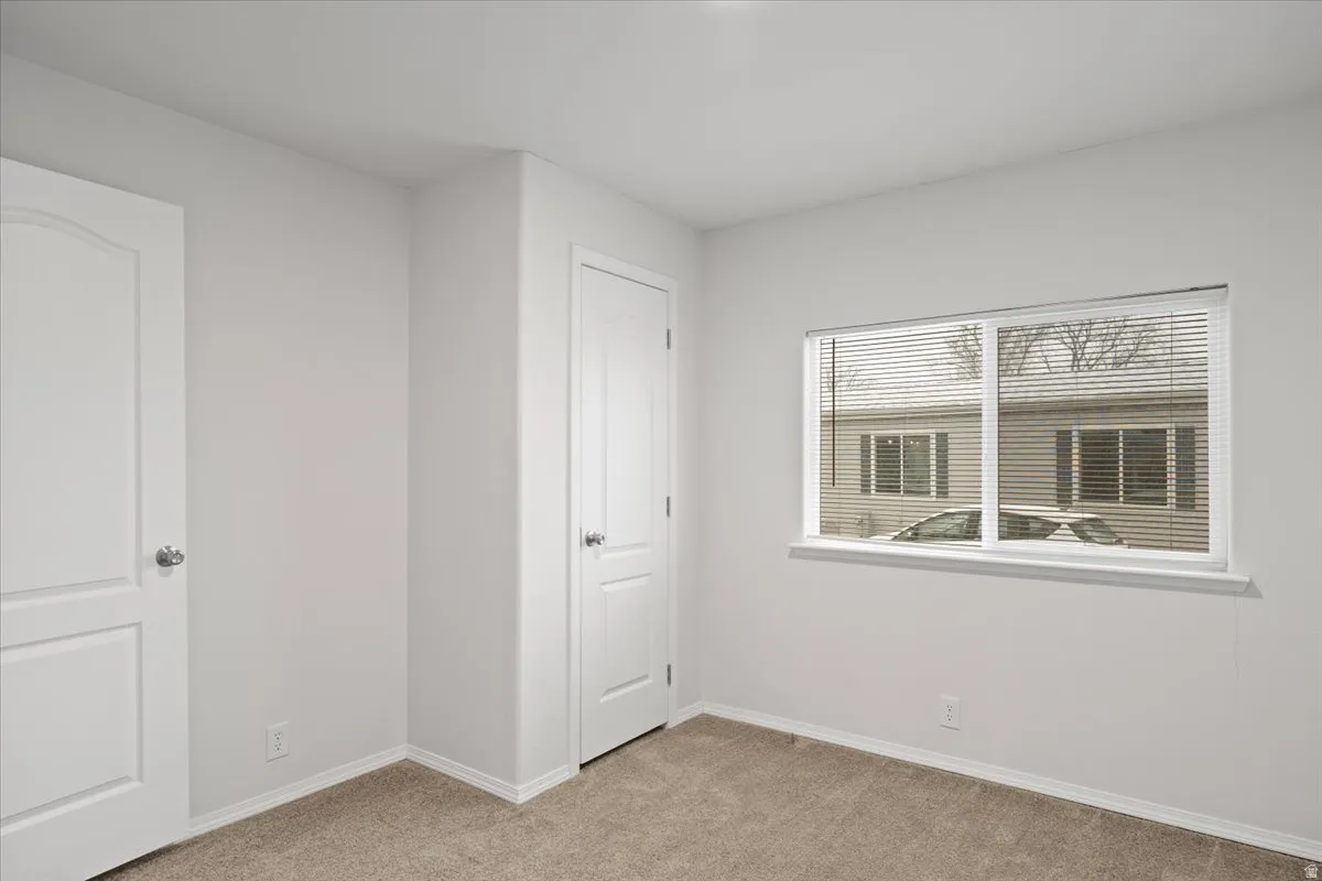 Unfurnished bedroom featuring light carpet and baseboards